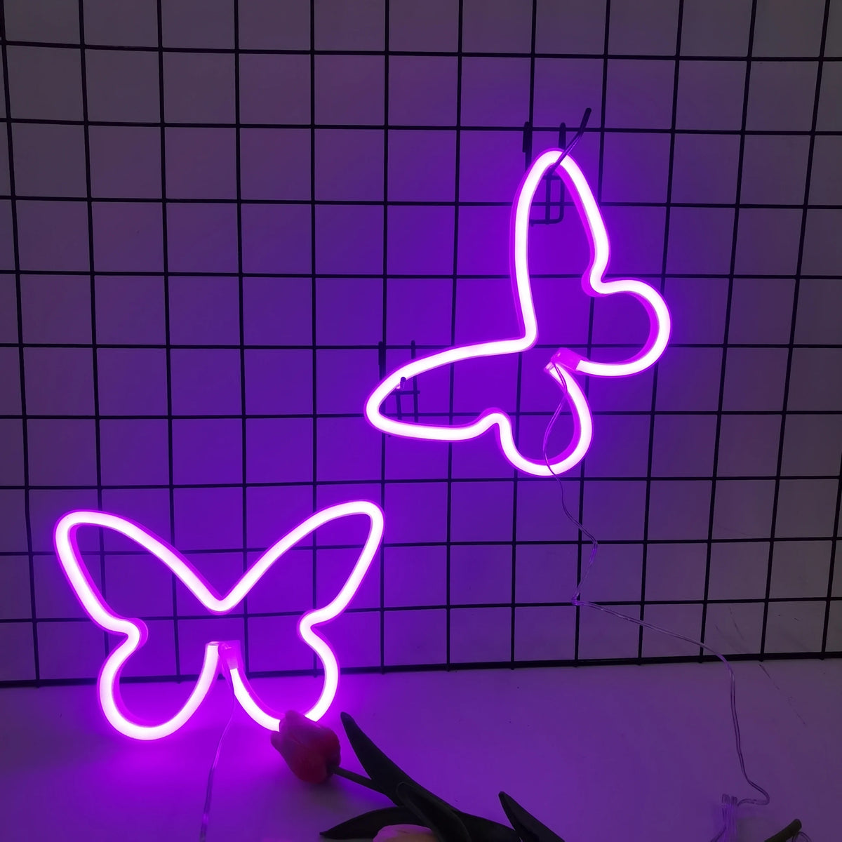 A bright neon pink butterfly sign is displayed against a dark grid background.
