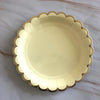 A gold disposable party tableware set featuring a decorative plate with scalloped edges.