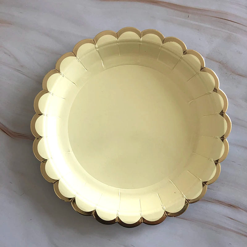 A gold disposable party tableware set featuring a decorative plate with scalloped edges.