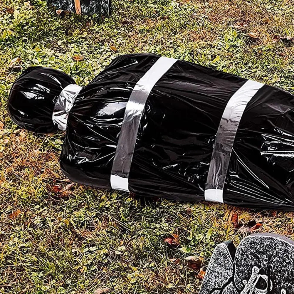A black plastic bag with silver stripes lying on green grass.