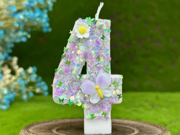 A number cake candle shaped like the number 4 decorated with purple and white flowers and butterflies