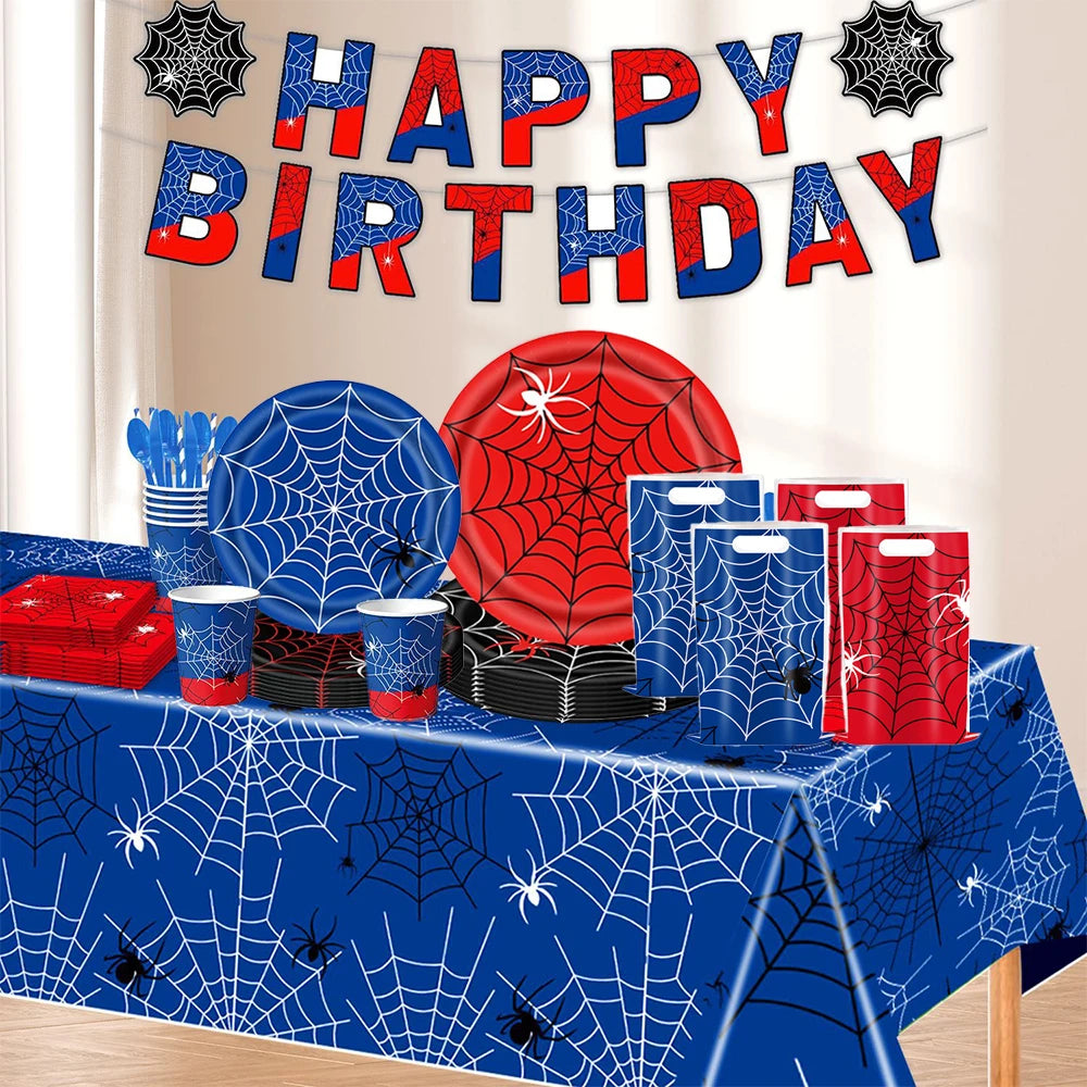 A table display featuring a red and blue spider web party banner, red and blue decorations, and various party supplies.