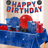 A table display featuring a red and blue spider web party banner, red and blue decorations, and various party supplies.