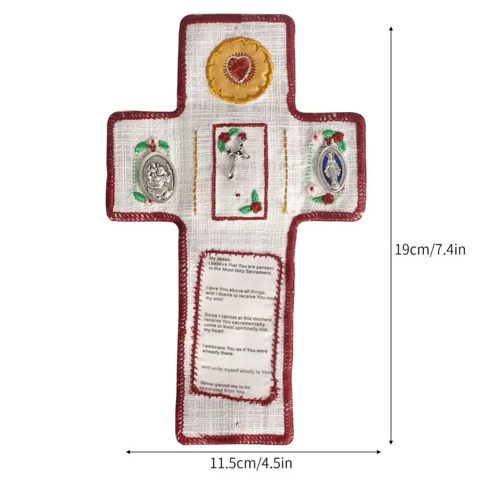 Hand sewn silver prayer cross decoration with floral accents on a white fabric background