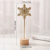 A golden iron snowflake ornament on a wooden stick with measurements shown.