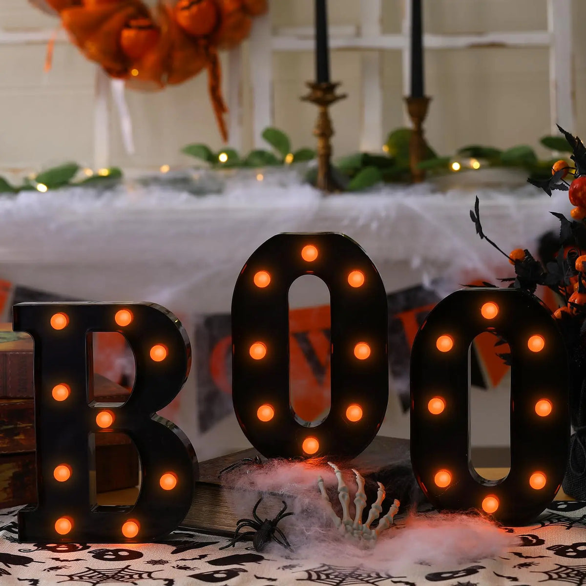 Un letrero de marquesina negro con forma de BOO y luces naranjas brillantes, colocado sobre una mesa.