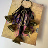 Decorative metal wind chimes with dark leather accents displayed on aged paper.