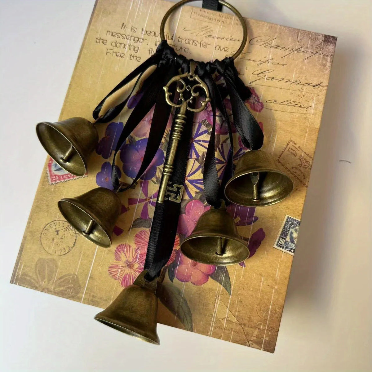 Decorative metal wind chimes with dark leather accents displayed on aged paper.
