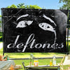 A black flag tapestry featuring a white stylized eye design and the band name Deftones.
