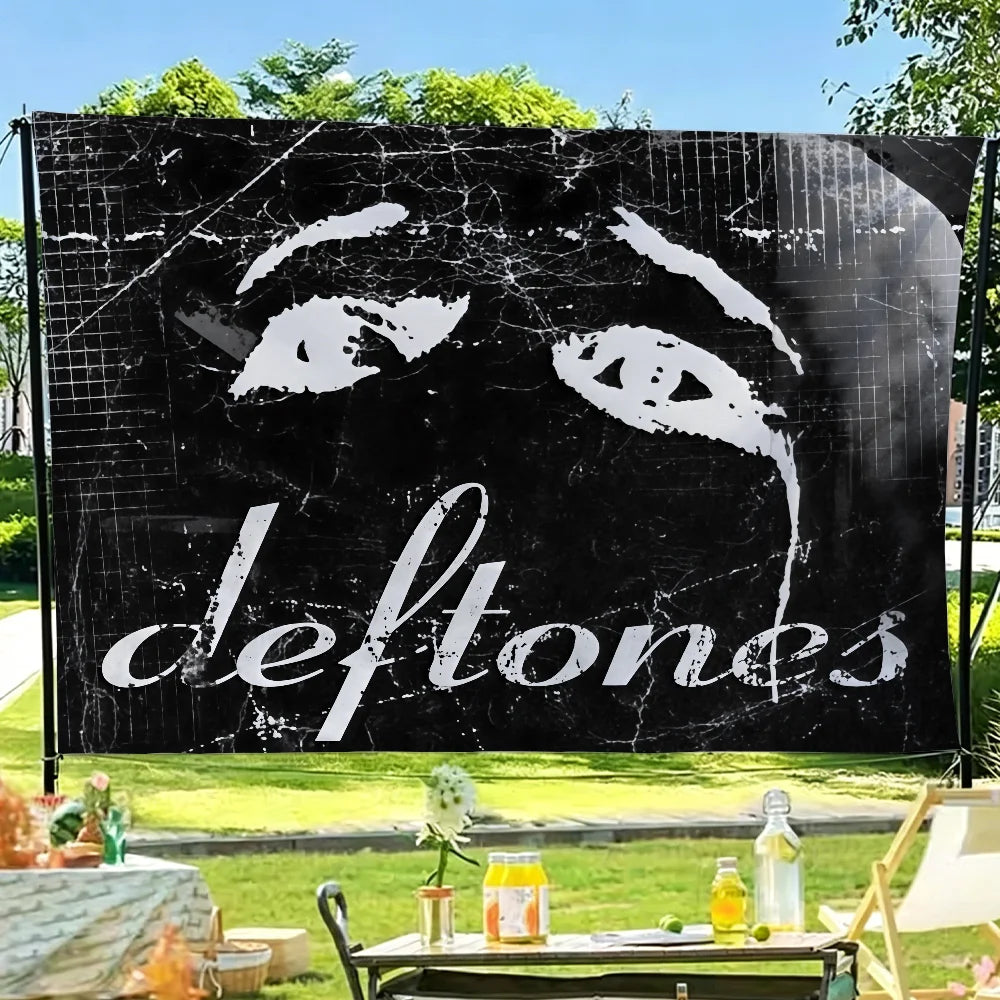 A black flag tapestry featuring a white stylized eye design and the band name Deftones.