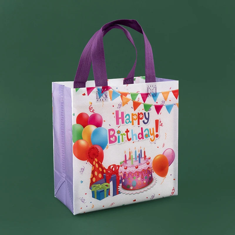 A white reusable happy birthday gift bag with purple handles and colorful bunting, featuring a pink birthday cake and balloon