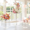 Elegant transparent acrylic cake display rack with pink and peach floral arrangements.