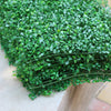 Green artificial grass hedge panels arranged in a curved display for privacy and decoration.