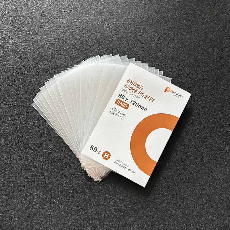 A stack of 50 clear protective card sleeves with orange branding is displayed on a dark surface.