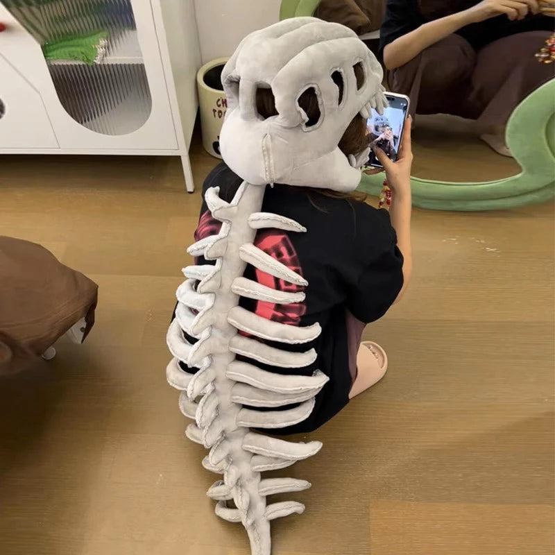 A person wearing a white dinosaur skeleton costume with a head and spine, sitting on a wooden floor.