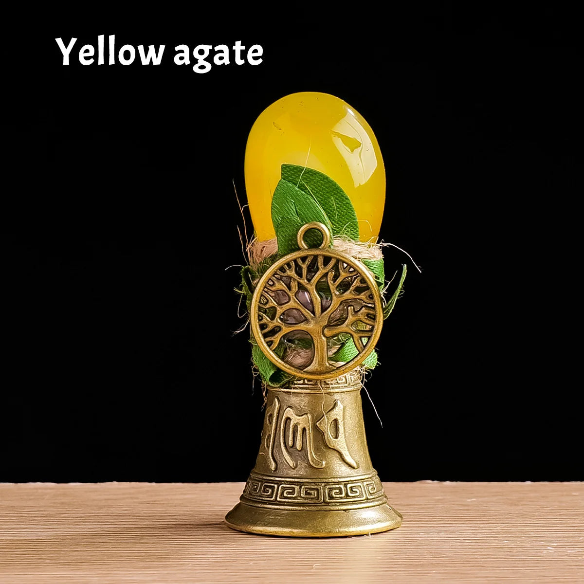 A yellow agate stone is displayed in a brass tree of life chime for meditation and decor.