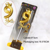 A gold 9-shaped candle with a crown topper is shown inside its packaging box.