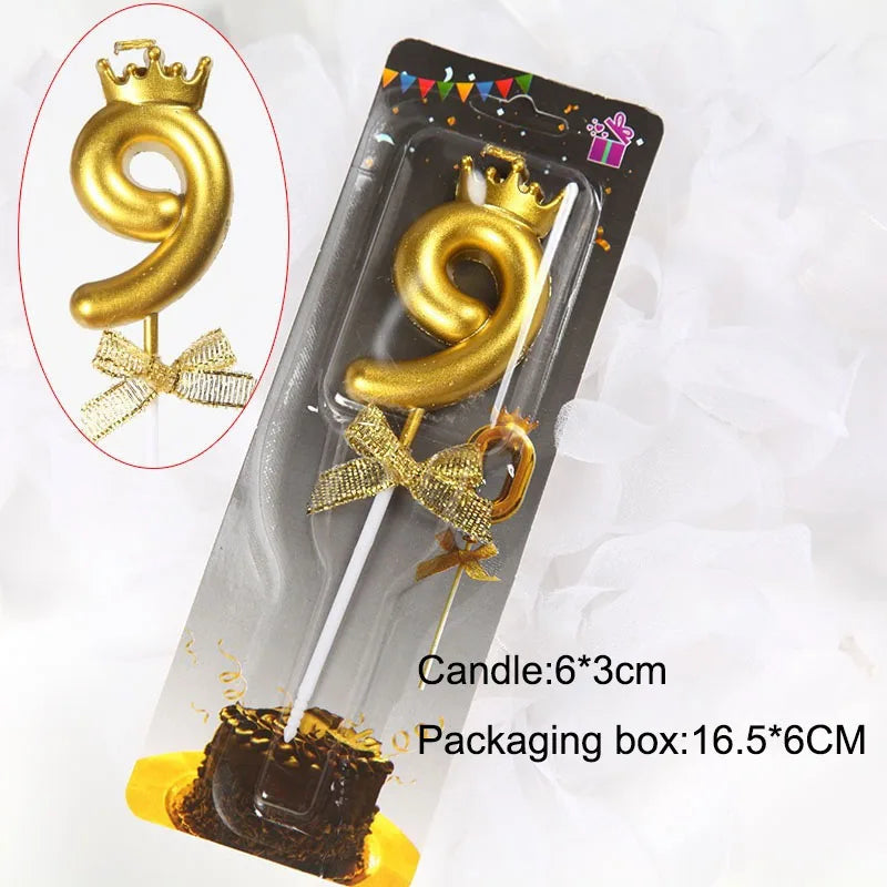A gold 9-shaped candle with a crown topper is shown inside its packaging box.