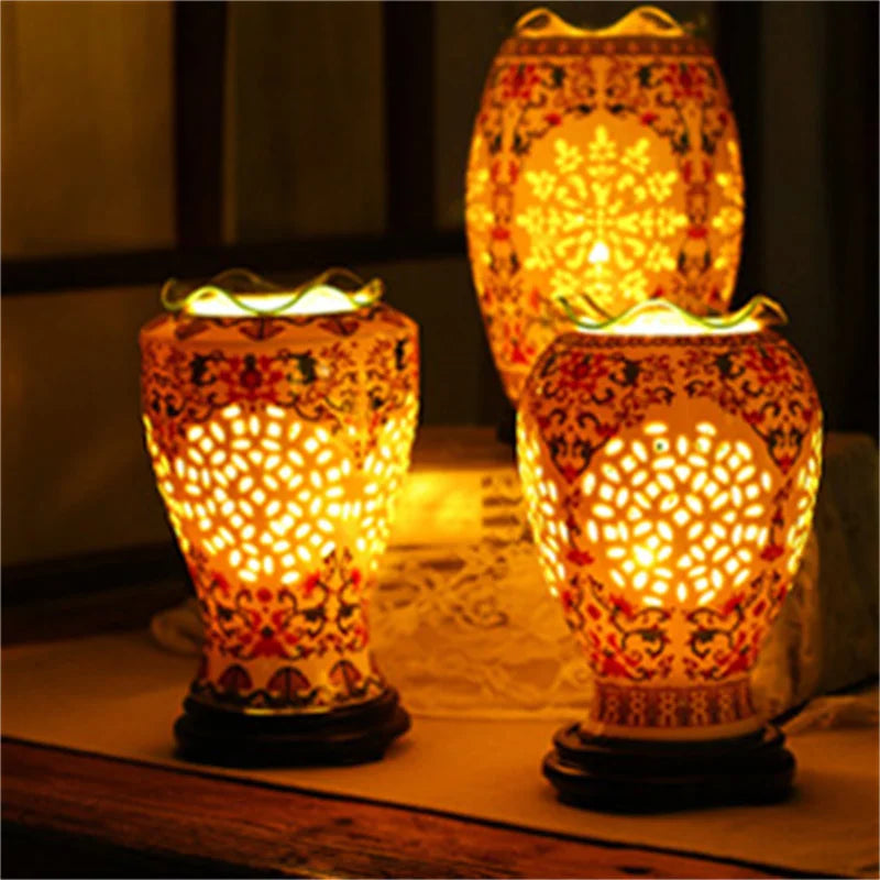 A pair of decorative oil lamps with intricate patterns and warm yellow light sitting on a wooden surface.