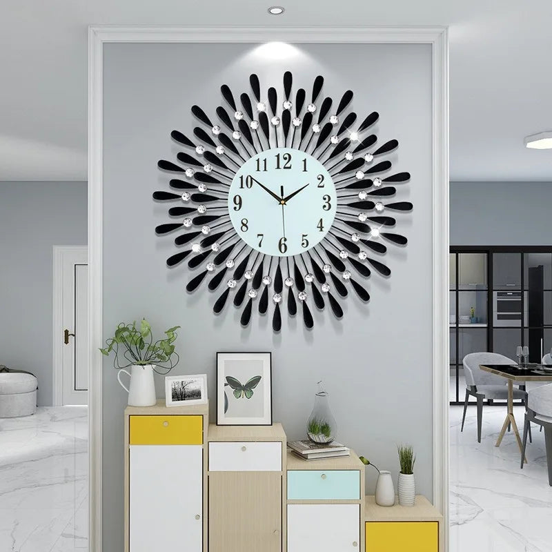 A modern minimalist metal wall clock with a black and silver sunburst design is displayed on a light gray wall.