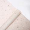 Roll of light pink decorative packaging paper with scattered orange flower petals.
