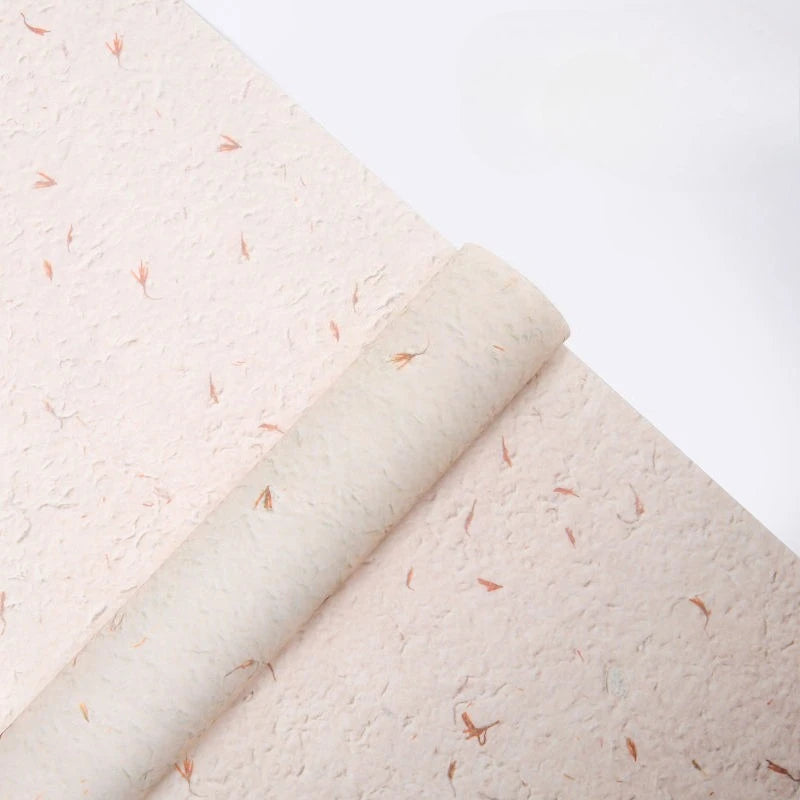 Roll of light pink decorative packaging paper with scattered orange flower petals.