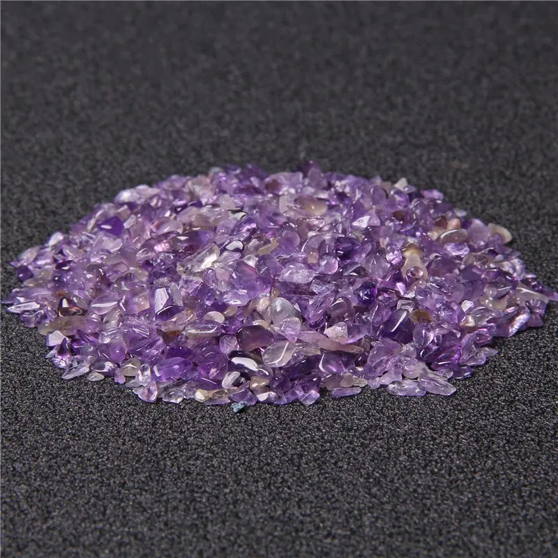 Pila de piedras de cuarzo amatista púrpura pulidas sobre una superficie gris oscura.