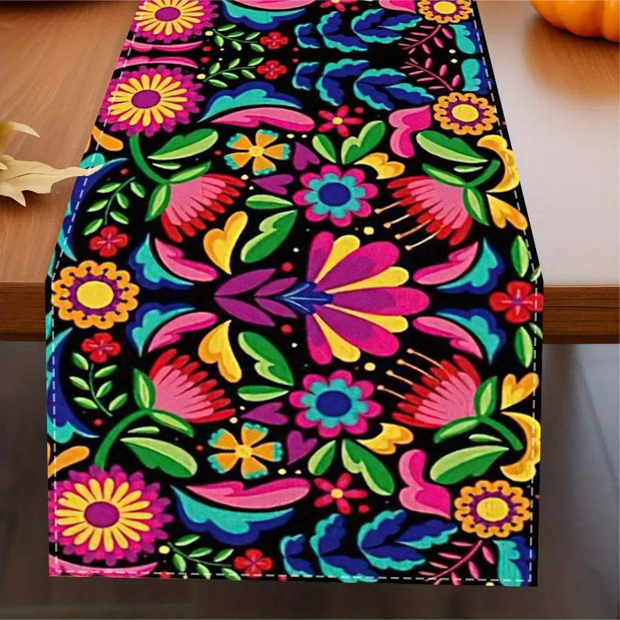 A vibrant linen table runner featuring a colorful Mexican floral pattern on a wooden table.