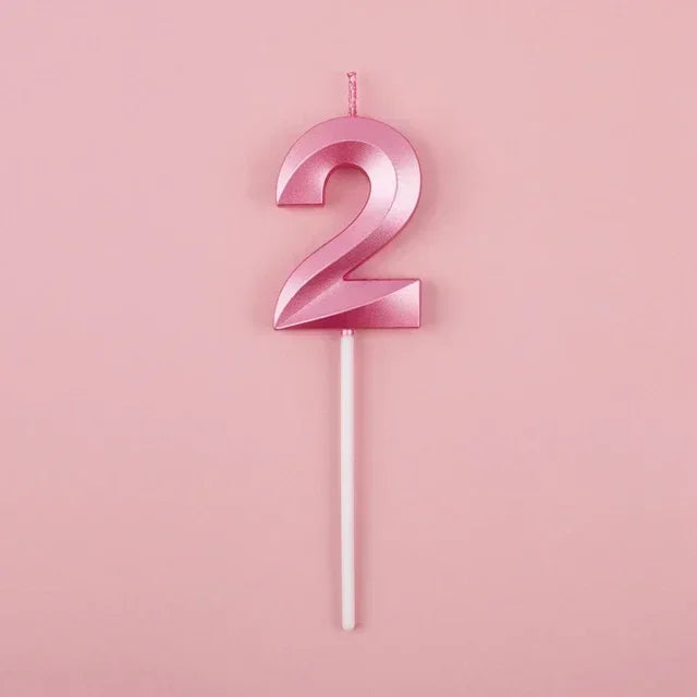 A pink number two candle on a white stick against a light pink background.