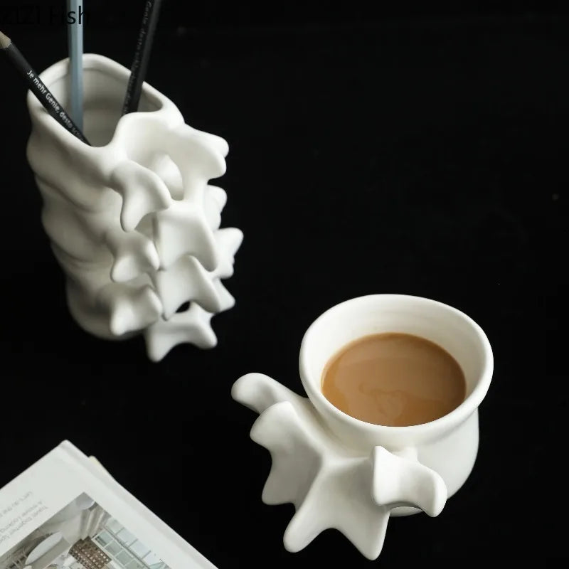 A white ceramic vase shaped like a vertebra holds a cup of coffee on a dark surface.