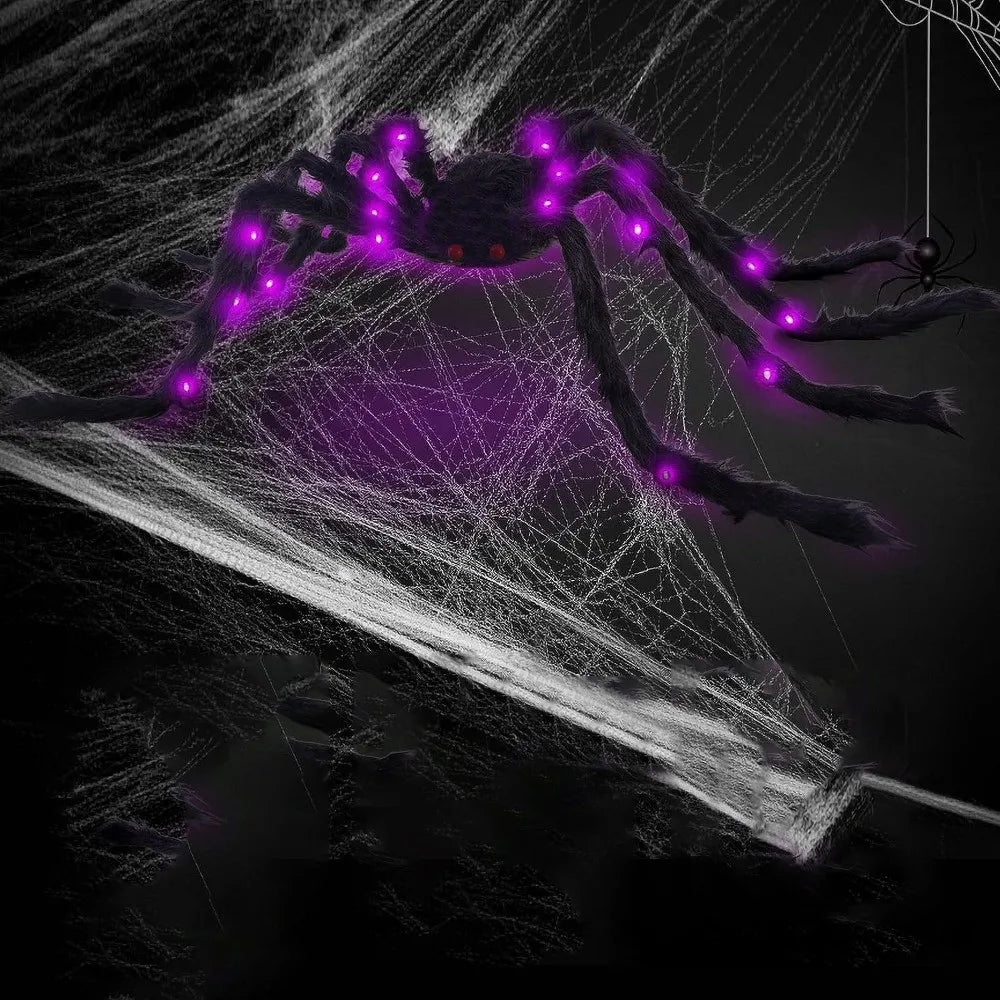 A dark spider decoration with glowing purple LED lights is suspended in a white web against a black background.