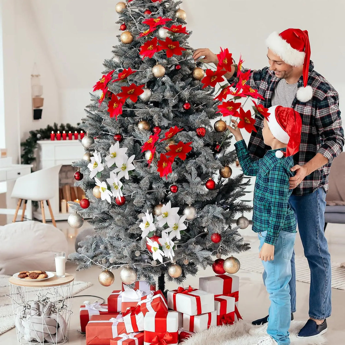 A man and a young boy decorating a Christmas tree with artificial poinsettia leaves and ornaments.