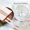 A wax core holder with wooden sticks is shown next to a glass bowl and some wooden wicks.