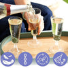 A hand pours champagne into an elegant disposable glass on a wooden board with various related icons.