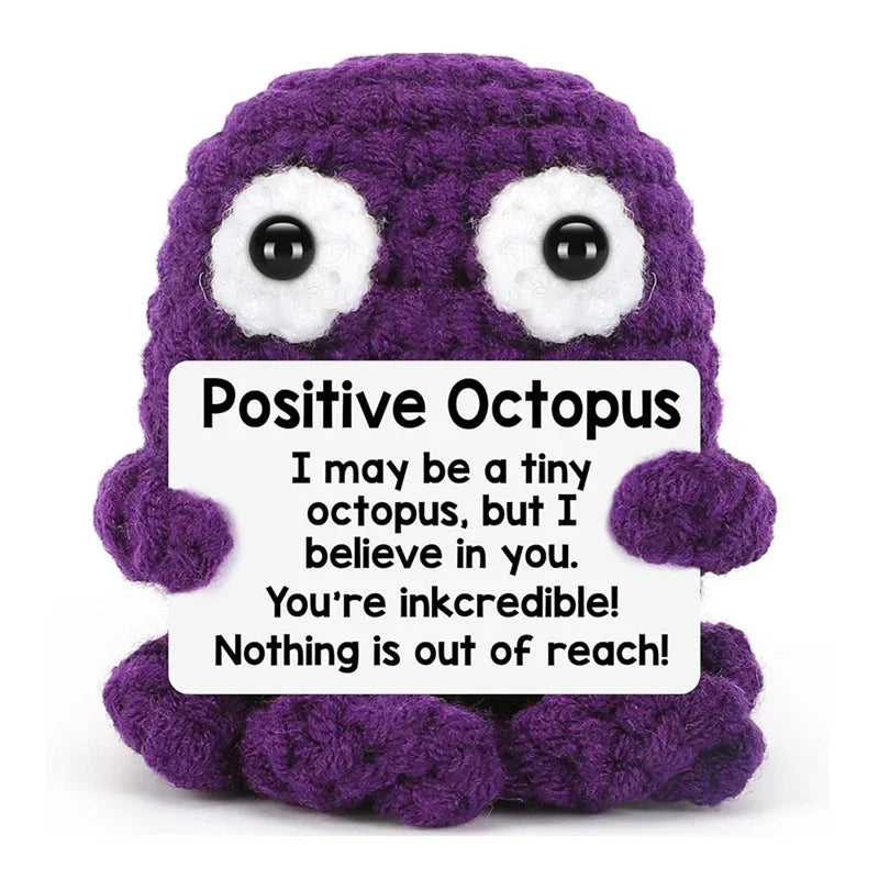 A purple crocheted octopus toy with a white message card that reads I may be a tiny octopus but I believe in you.