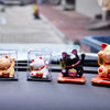 A collection of solar-powered waving lucky cat figurines in various colors and styles displayed on a dark surface.