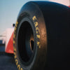 Close-up of a black racing tire with yellow lettering resting on a dark surface.