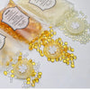 Various clear and amber wax sealing beads are displayed on a white surface.
