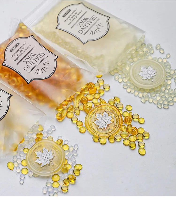 Various clear and amber wax sealing beads are displayed on a white surface.