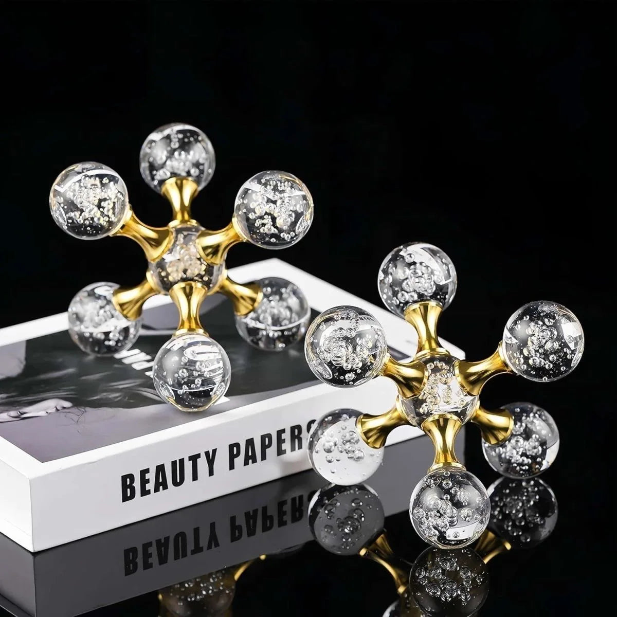 Gold molecular sculpture desk decor featuring clear glass spheres on a white box.