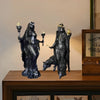 A dark resin statue of a goddess with horns and mystical details, standing next to a reclining figure.