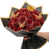 A bouquet of ten deep red glitter roses with a gold crown decoration presented in a black paper holder.