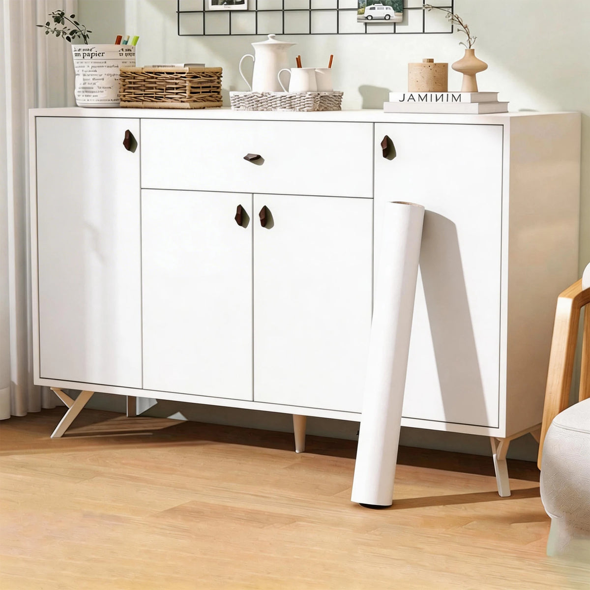 A white cabinet with drawers and doors decorated with matte peel and stick decor stickers on a wooden floor.