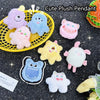 A collection of cute fuzzy plush monster pendants in various colors like purple blue pink and yellow against a dark backgroun