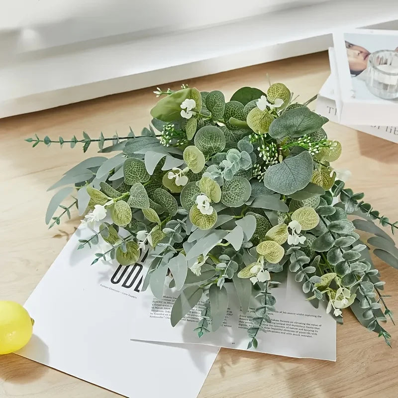 A lush bouquet of mixed green eucalyptus and willow artificial flowers displayed on a white paper.