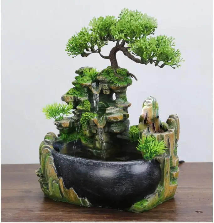 A resin desktop fountain featuring a mossy rock structure and a miniature green tree.