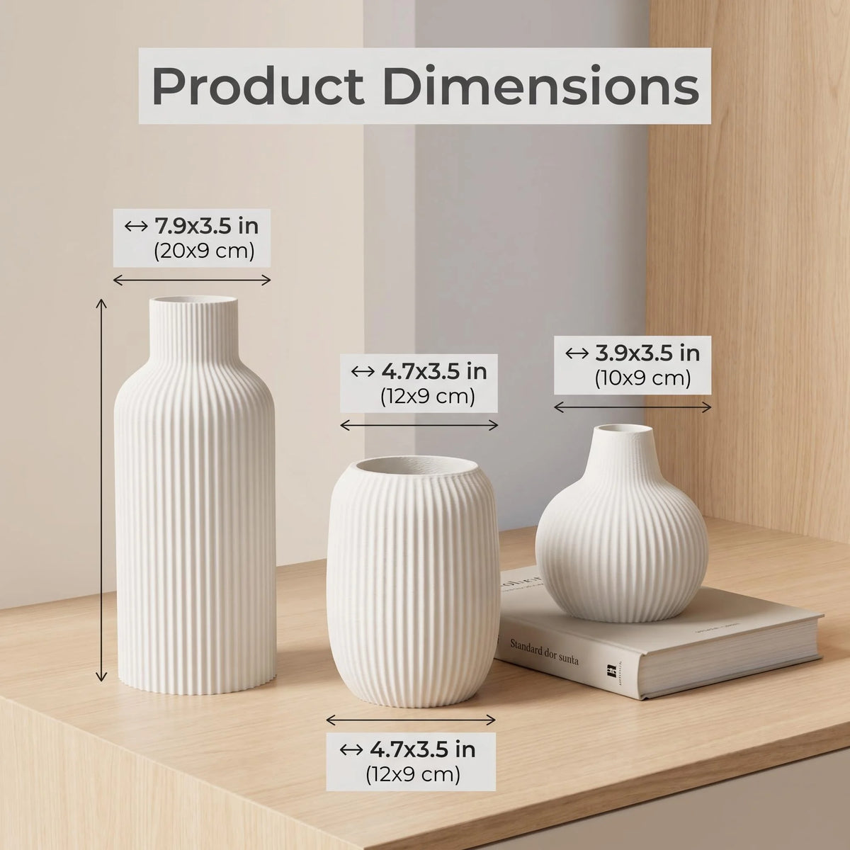 A set of three matte white ceramic vases with vertical ribbed texture shown next to a book and dimension labels.