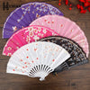A collection of five folding fans in various shades of pink, purple, and black with floral patterns.