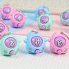 A collection of colorful mini rock-paper-scissors themed keychains in pink, purple, and teal resting on a white grid.