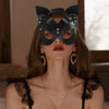 A model wearing an elegant black fox masquerade mask with silver studs and a delicate gold necklace.